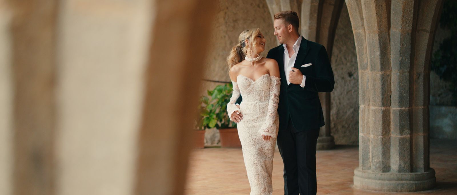 Chelsea and Nicholas walking beneath the arches at Villa Cimbrone