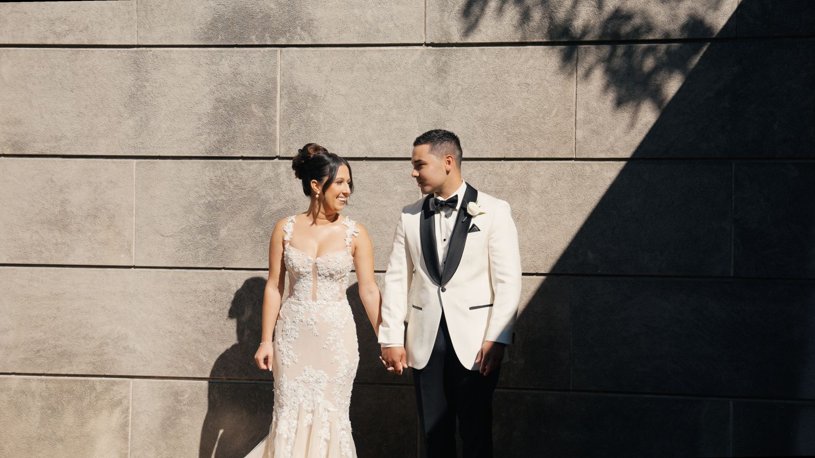 Martin and Elizabeth holding hands against a sunlit stone wall