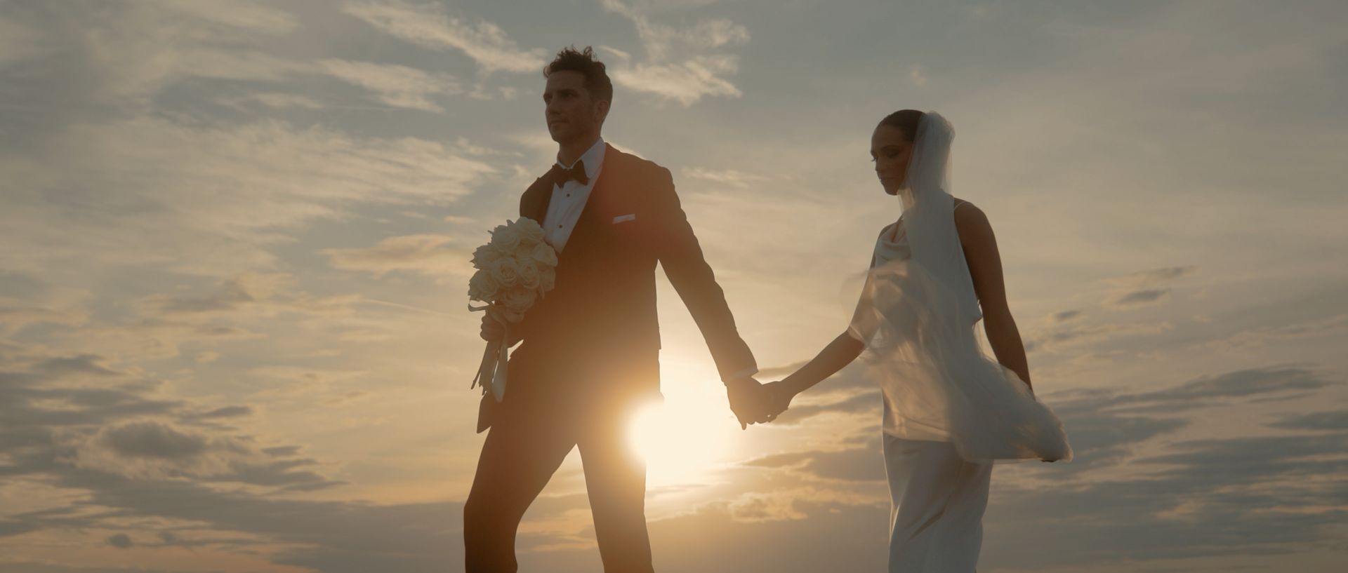 Mia and Jay walking hand in hand at sunset