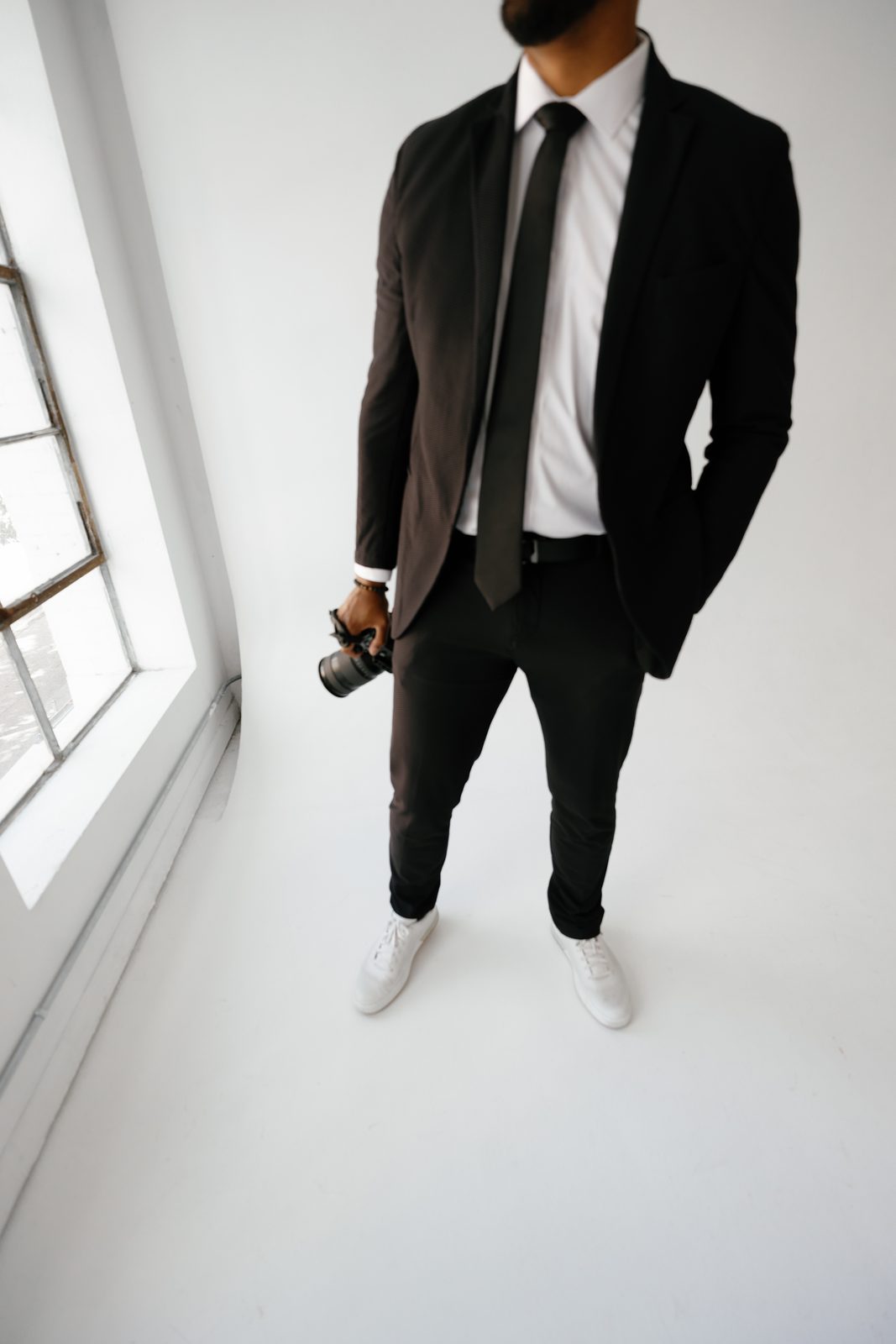 Close crop of Javi in a suit holding a camera by a window