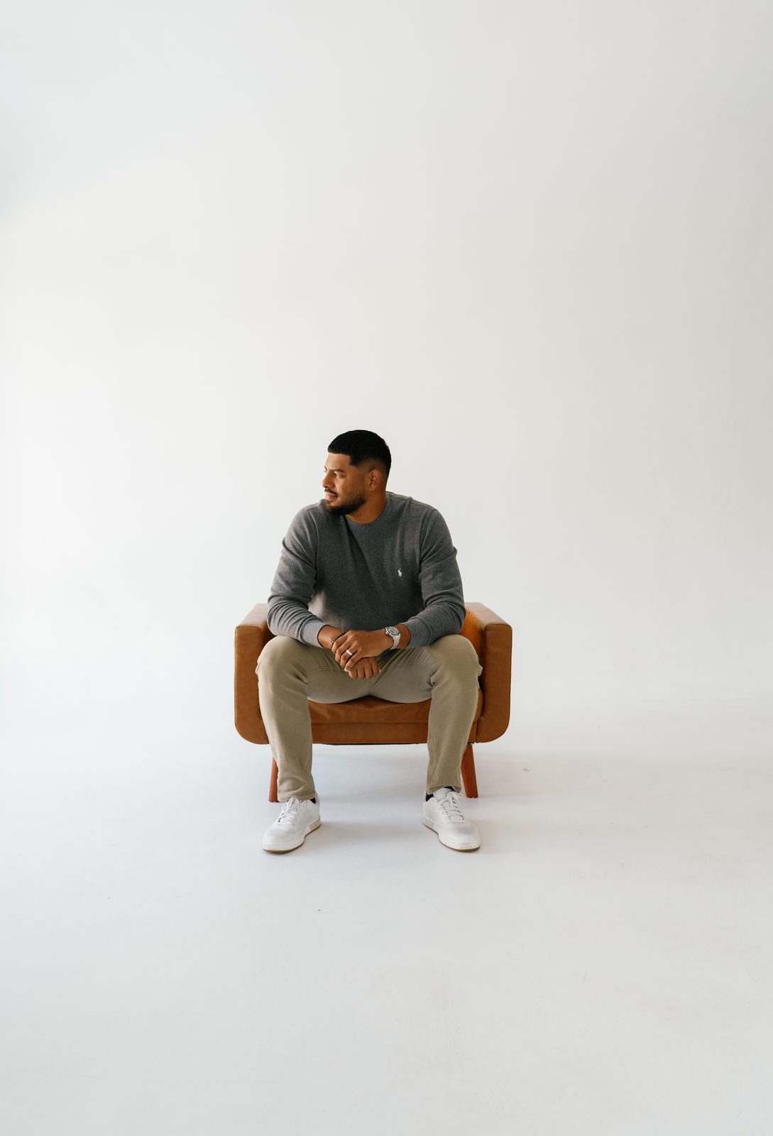 Javi seated in a leather chair in a gray sweater