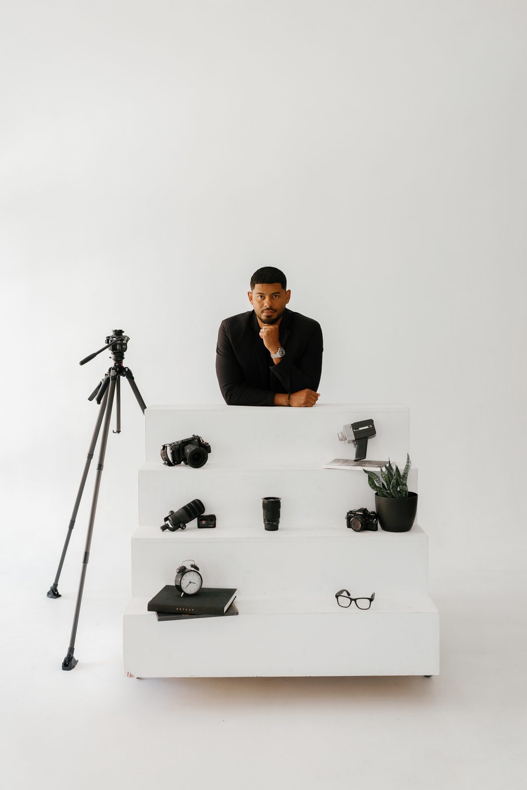Javi behind white steps lined with cameras and film gear