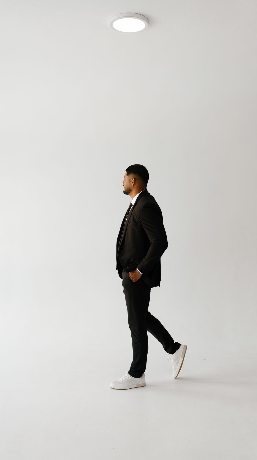 Javi walking in profile in a black suit
