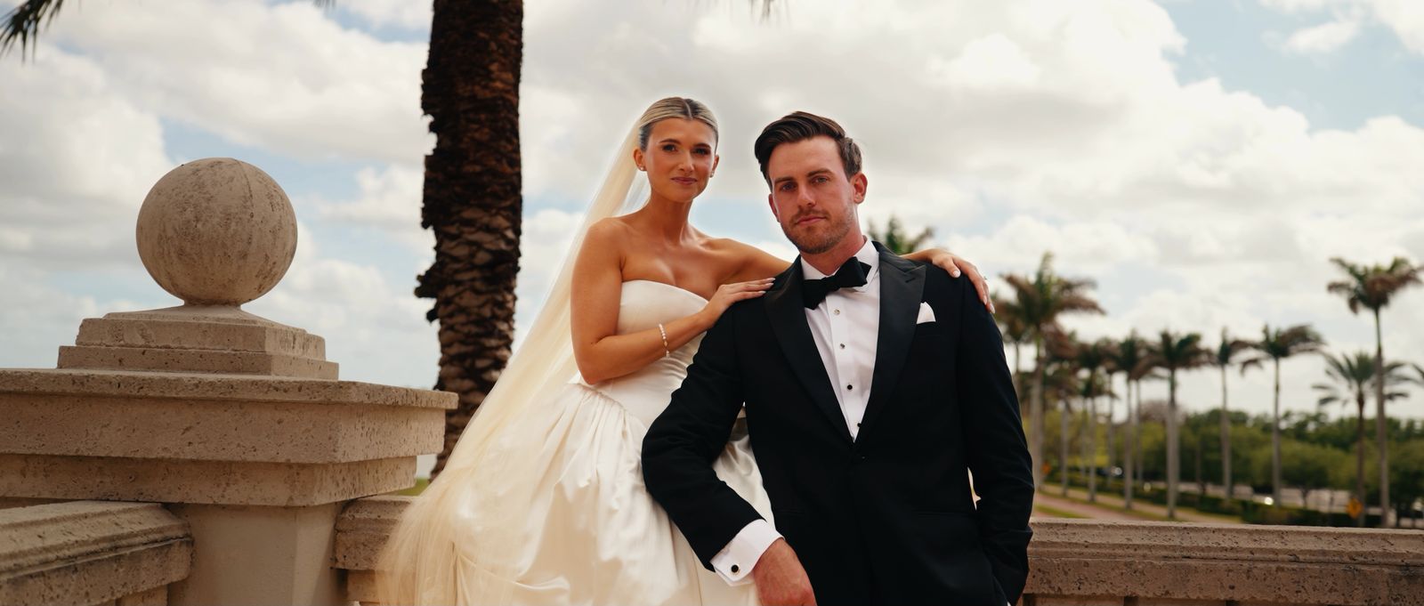Taylor and Danny posing on a stone balustrade under the palms